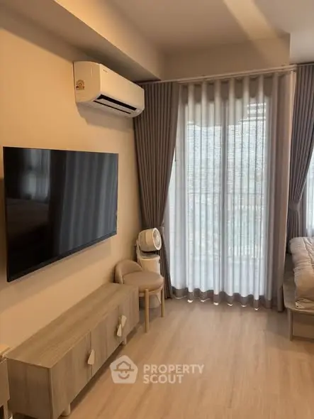 Modern living room with large TV, air conditioning, and elegant curtains in a cozy apartment.
