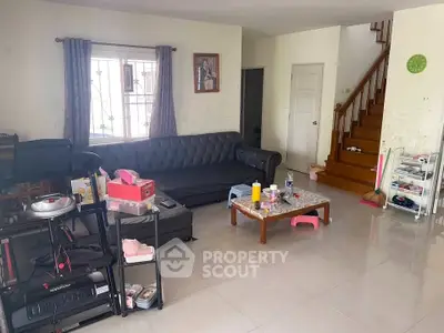 Spacious living room with modern furniture and staircase, ideal for family gatherings.