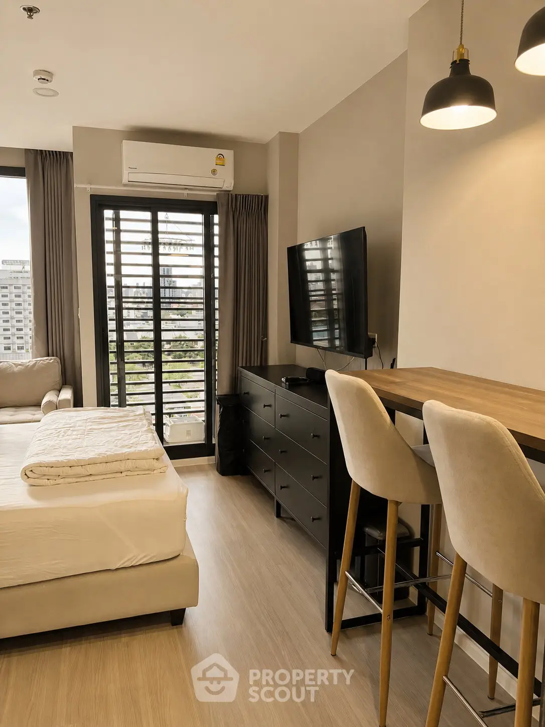 Modern studio apartment with stylish decor and city view, featuring a cozy bed, sleek TV setup, and elegant lighting.