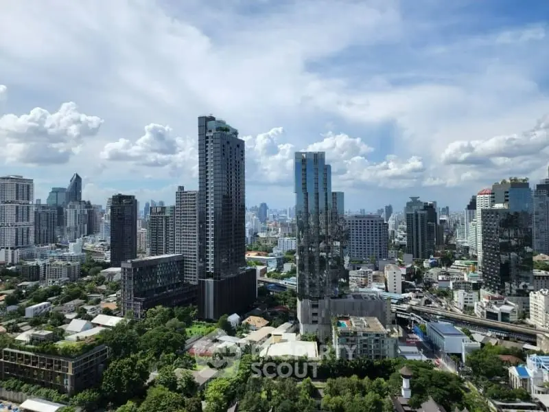 Stunning cityscape view of modern skyscrapers and lush greenery under a vibrant blue sky.