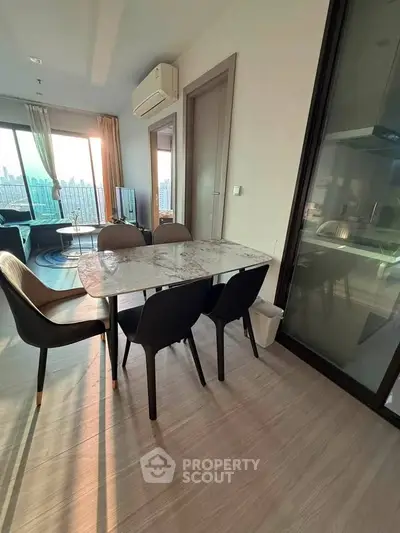 Modern dining area with elegant marble table and stylish chairs in a sunlit apartment.
