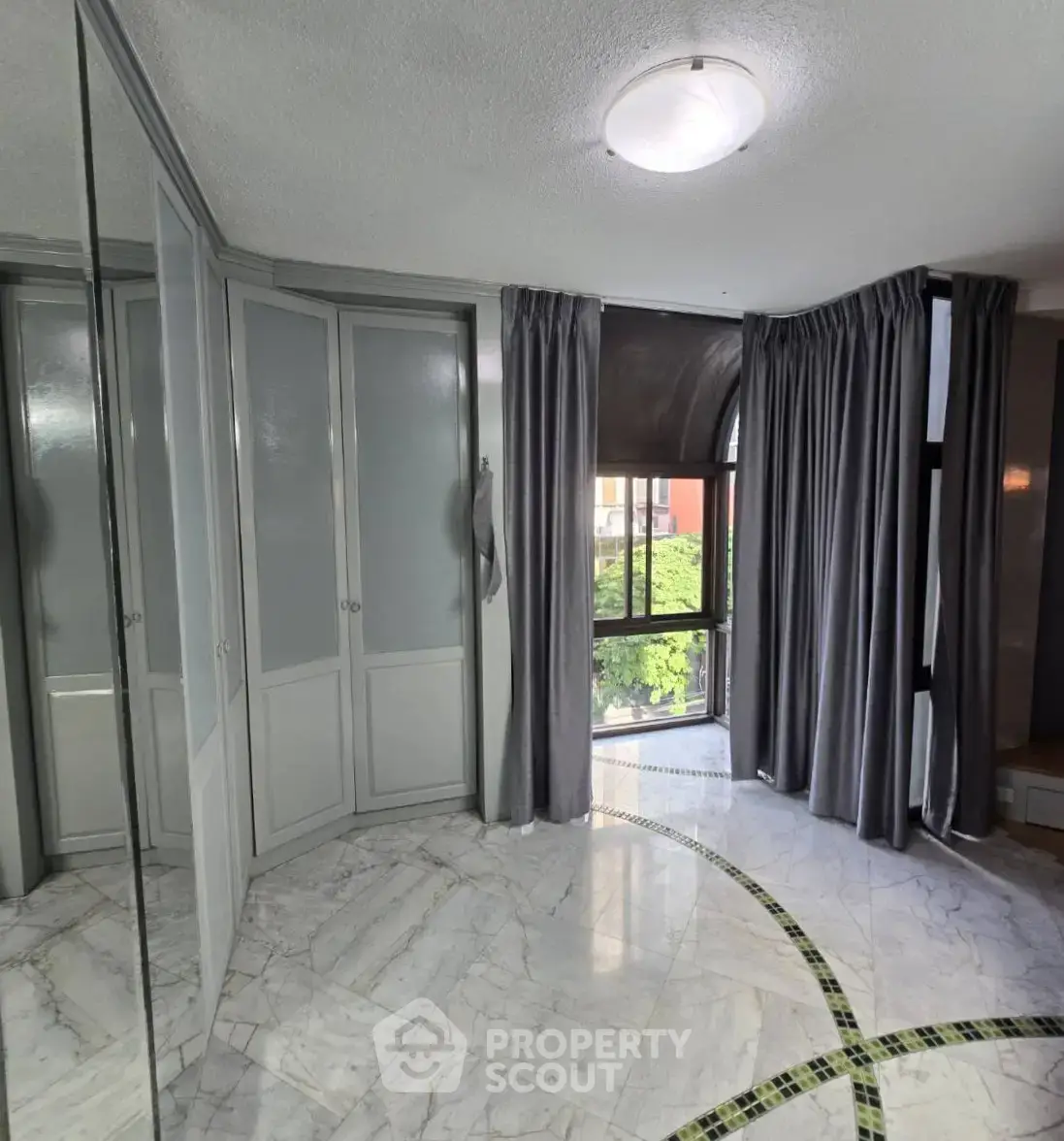 Spacious bedroom with elegant marble flooring and large windows for natural light.