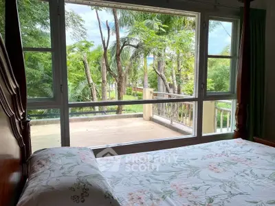 Spacious bedroom with large window offering a serene garden view, perfect for relaxation and tranquility.
