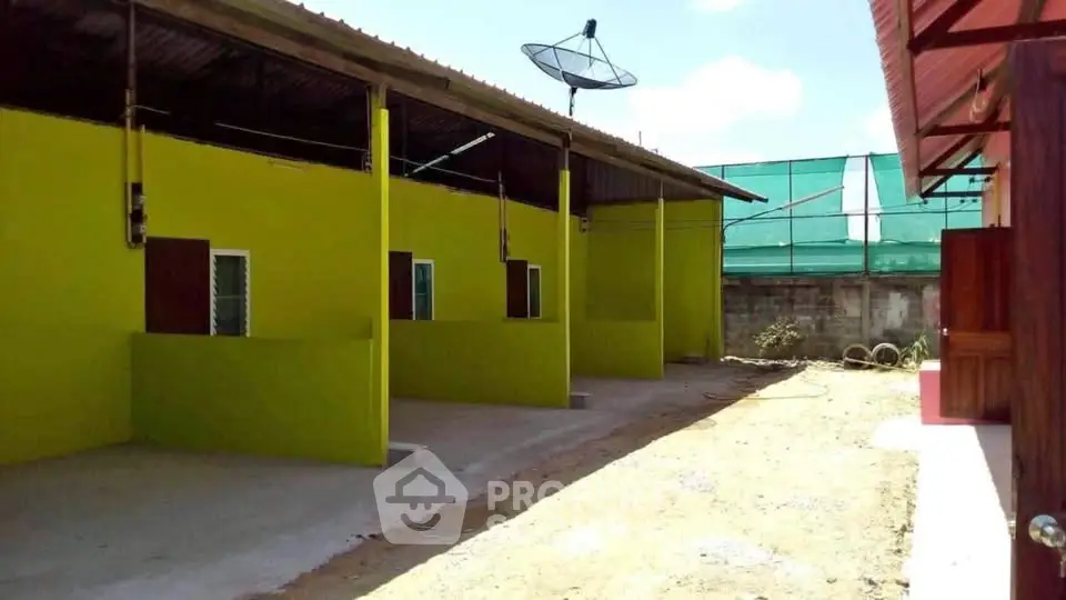 Vibrant green exterior of a residential building with satellite dish and open space.