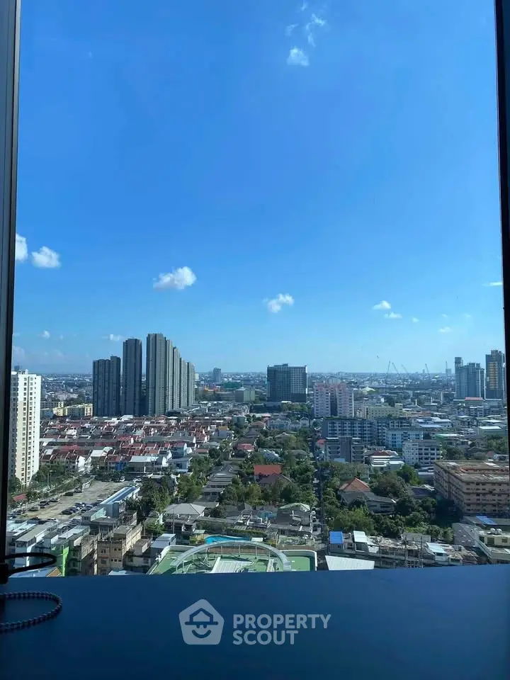 Stunning cityscape view from high-rise building window showcasing urban skyline and clear blue sky.