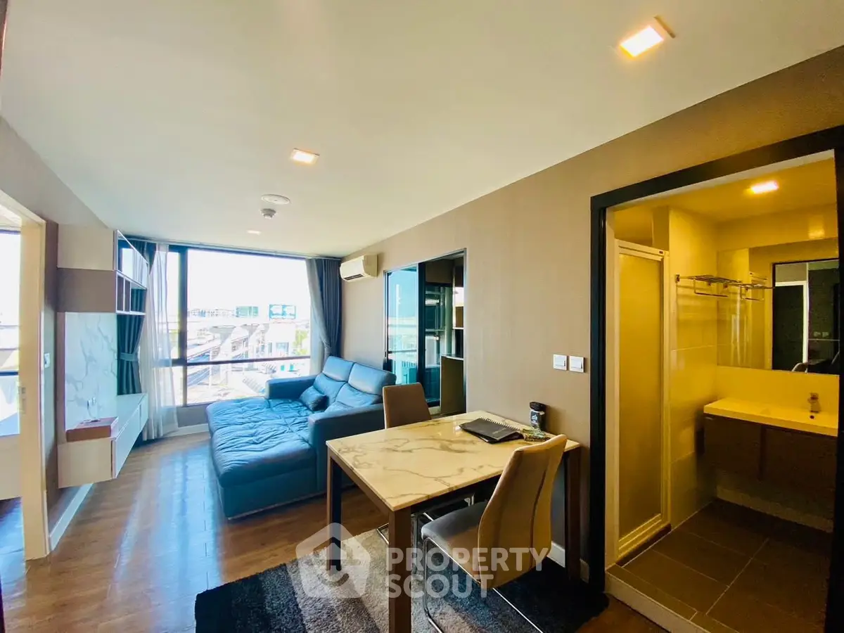 Modern living room with open layout and city view, featuring a cozy sofa and dining area.