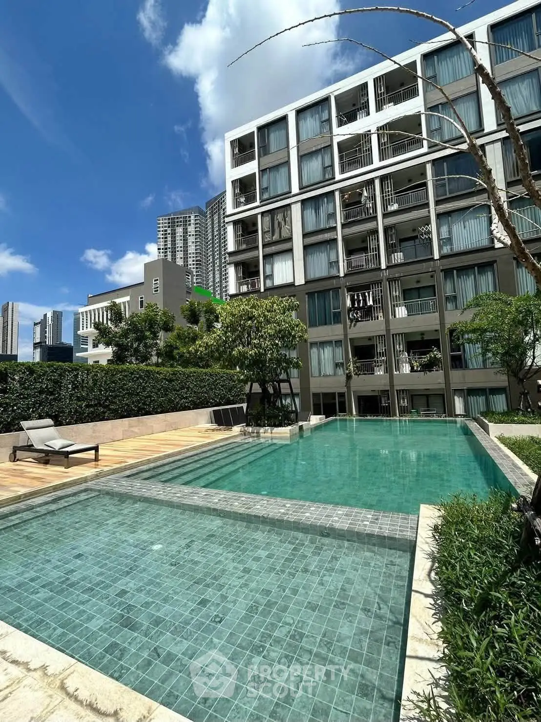 Modern apartment building with a luxurious outdoor pool and lush greenery.