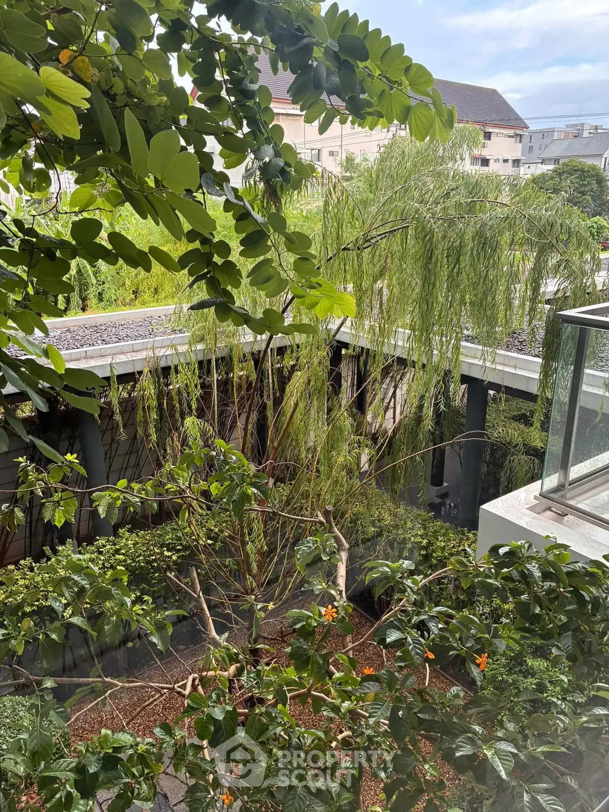 Lush garden view from a modern residential building balcony, showcasing vibrant greenery and serene surroundings.