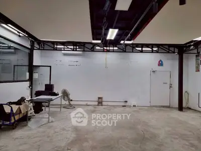 Spacious industrial-style room with high ceilings and exposed beams, ideal for creative workspace or studio.