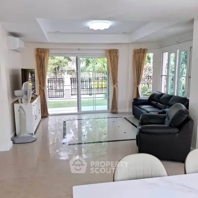 Spacious living room with modern furniture and large windows overlooking a lush garden.