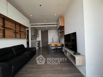Modern living room with open kitchen, sleek furniture, and wooden flooring in a stylish apartment.
