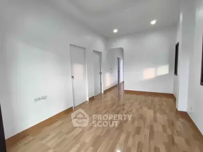 Spacious empty room with wooden flooring and white walls, ideal for customization.
