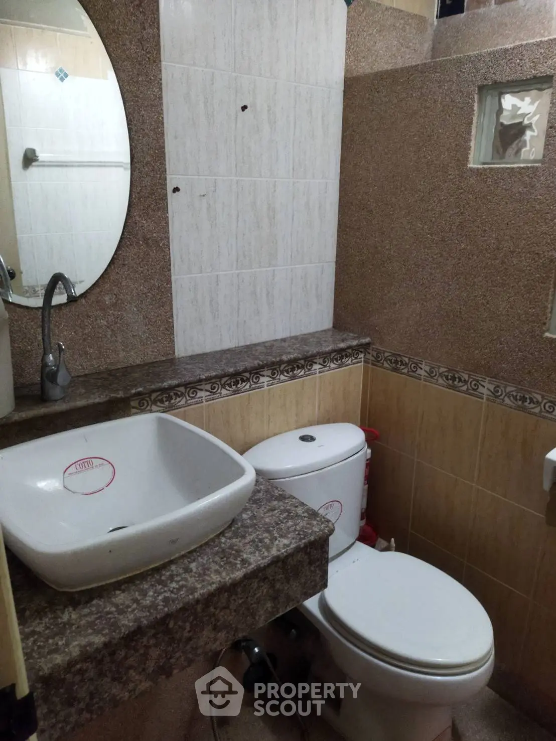 Compact bathroom with modern sink and toilet, featuring neutral tile design.