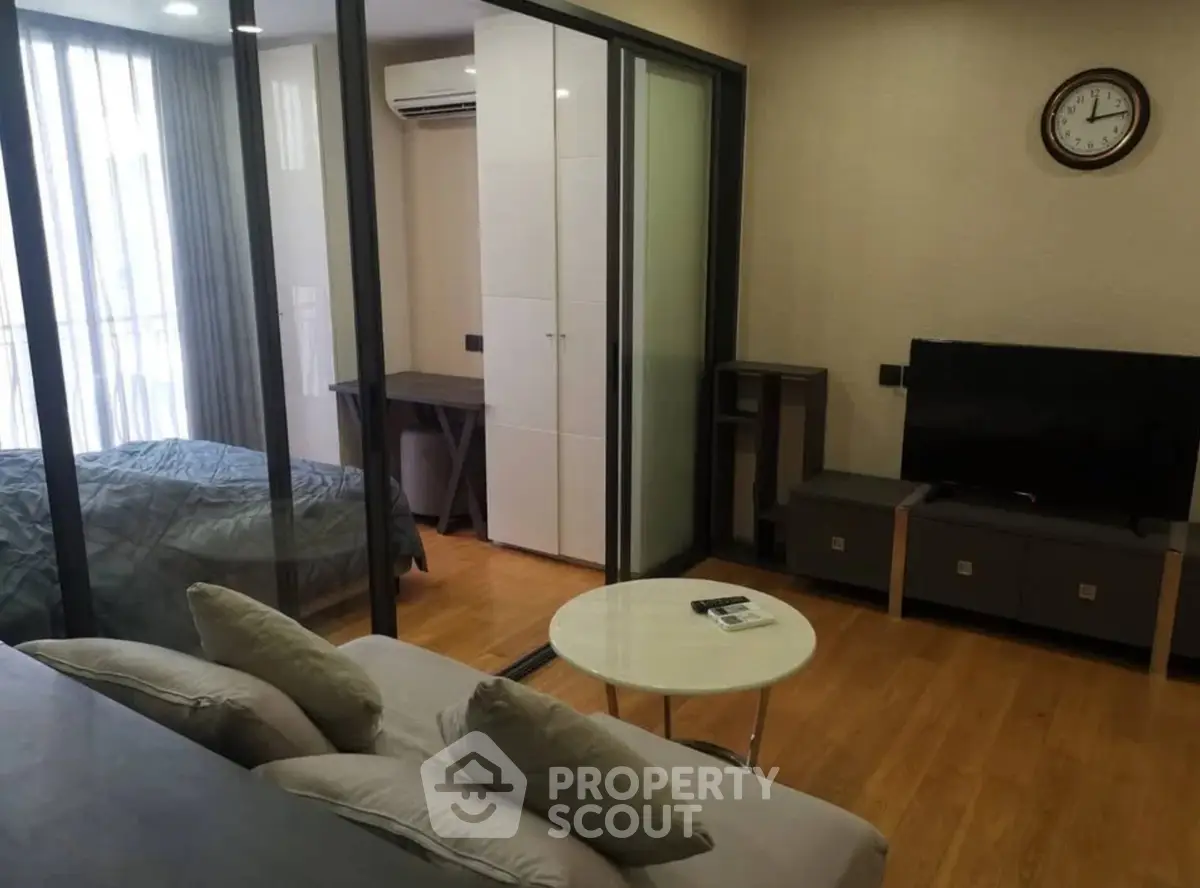 Modern studio apartment with glass partition, cozy living area, and sleek bedroom.