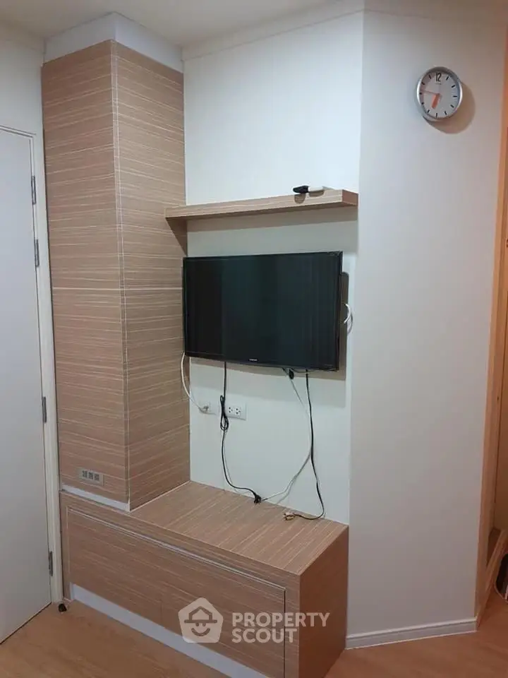 Modern living room corner with wall-mounted TV and stylish wooden paneling.