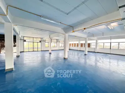 Spacious open-plan commercial space with large windows and blue flooring, ideal for office or retail use.