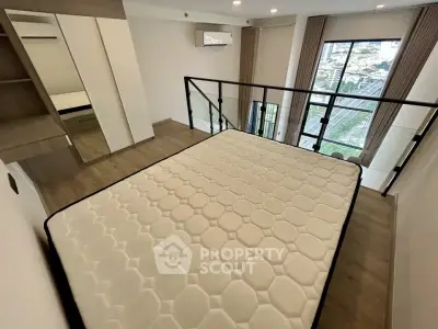 Modern bedroom with large window and city view, featuring a comfortable mattress and sleek design.