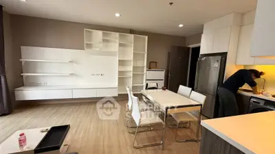 Modern open-layout kitchen and dining area with sleek white furniture and built-in shelving.