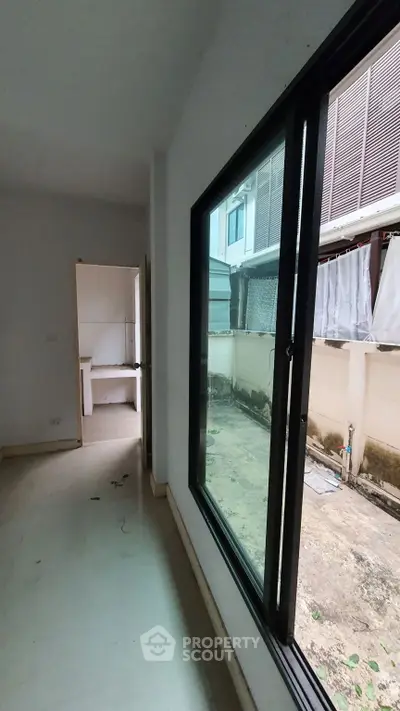 Spacious room with large window overlooking a private outdoor area, ideal for natural light.