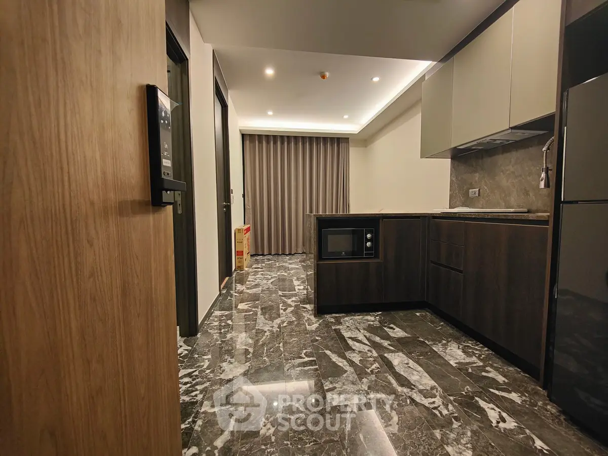 Modern kitchen with sleek cabinetry and marble flooring in a contemporary apartment.