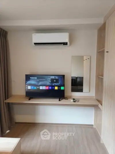 Modern living room with sleek TV setup and air conditioning, perfect for cozy entertainment.