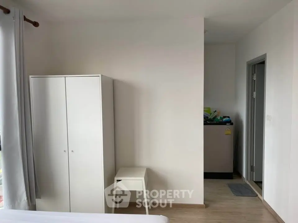 Modern minimalist bedroom with white wardrobe and washing machine corner.
