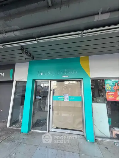 Commercial property exterior with teal facade and glass doors, ideal for retail or office space.