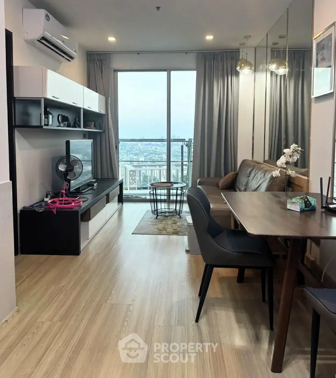 Modern living room with city view, stylish furniture, and wooden flooring in a high-rise apartment.