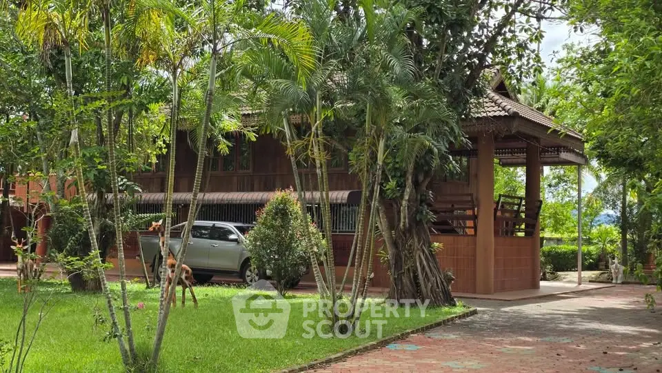 Charming wooden house with lush garden and carport in serene setting.