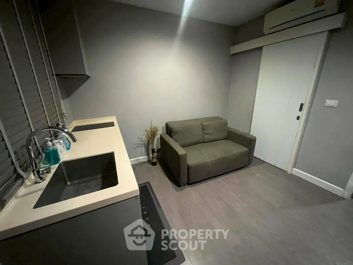 Compact living space with kitchenette and sofa, ideal for modern urban living.