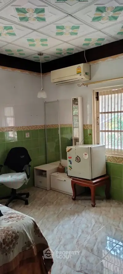 Cozy bedroom with air conditioning and small fridge, featuring tiled walls and ceiling decor.