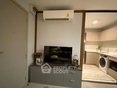 Modern living room with air conditioning and open kitchen layout featuring washing machine.