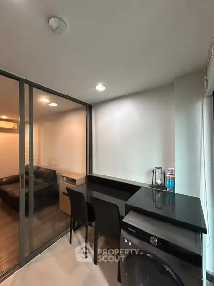 Modern apartment with sleek interior design featuring a compact dining area and washing machine.