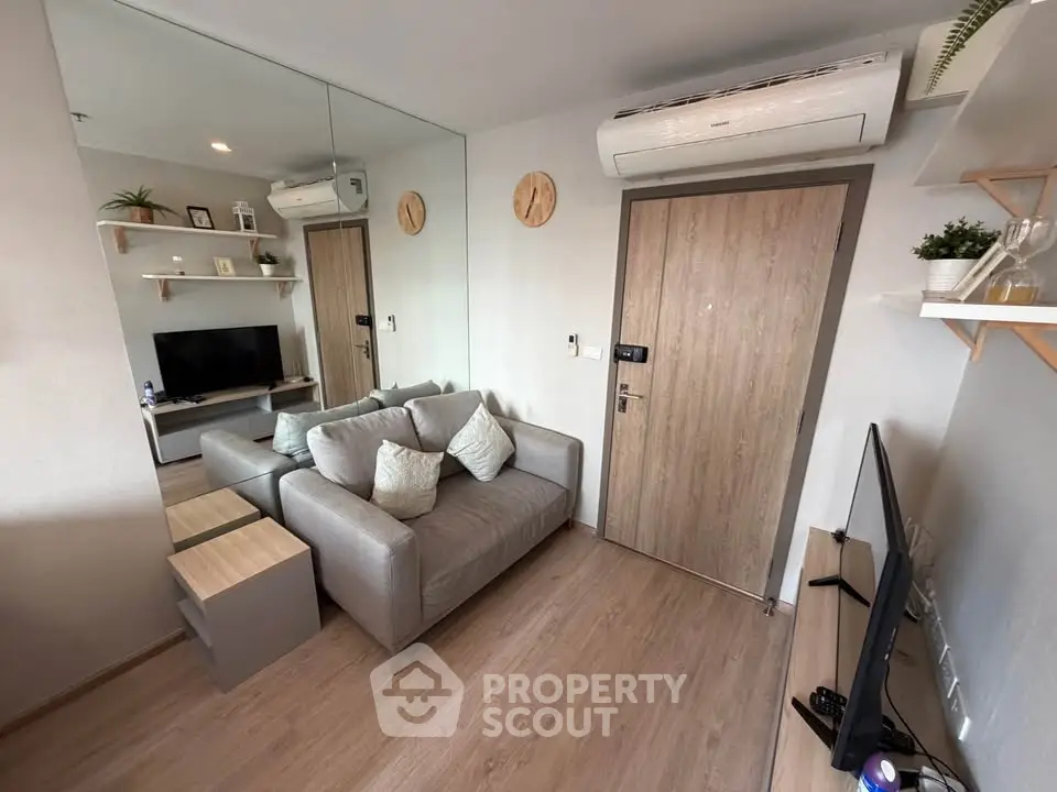 Modern living room with stylish decor and cozy seating area, featuring a wall-mounted TV and air conditioning.