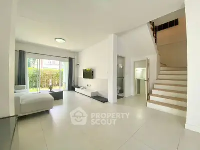 Spacious modern living room with sleek staircase and garden view, perfect for family gatherings.