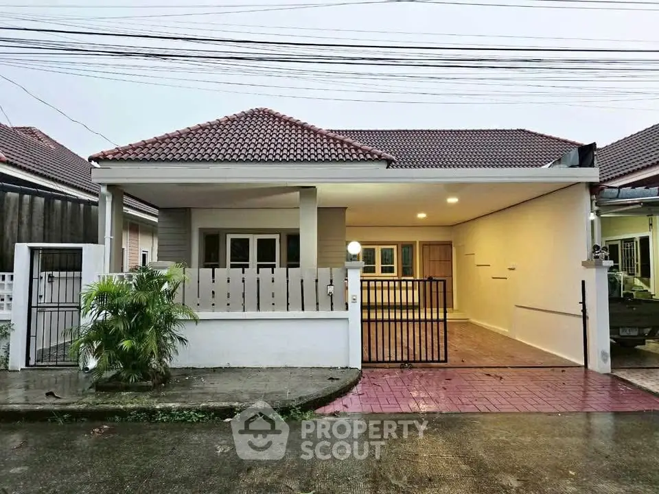 Charming single-story house with tiled roof and gated driveway in a serene neighborhood.