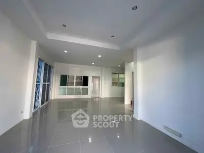 Spacious modern living area with sleek tile flooring and ample natural light.