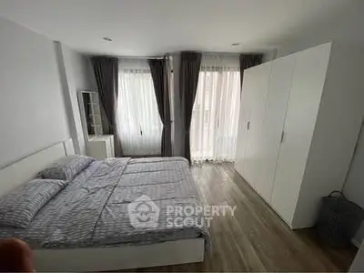 Spacious bedroom with modern decor and ample natural light, featuring a large bed and wardrobe.