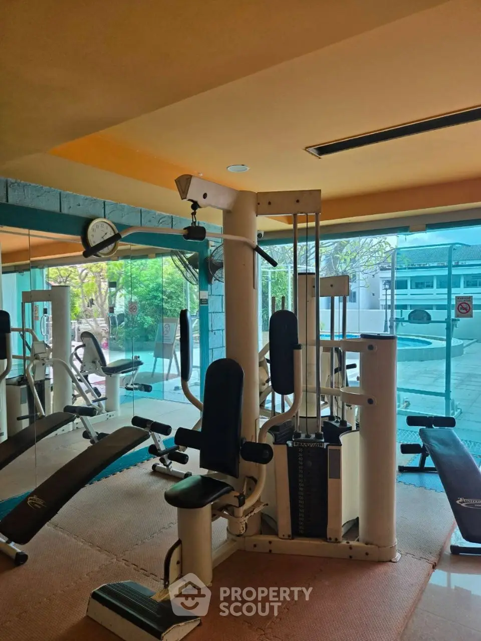 Spacious gym with modern equipment and pool view, perfect for fitness enthusiasts.