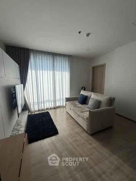 Modern living room with cozy sofa and natural light through large windows.
