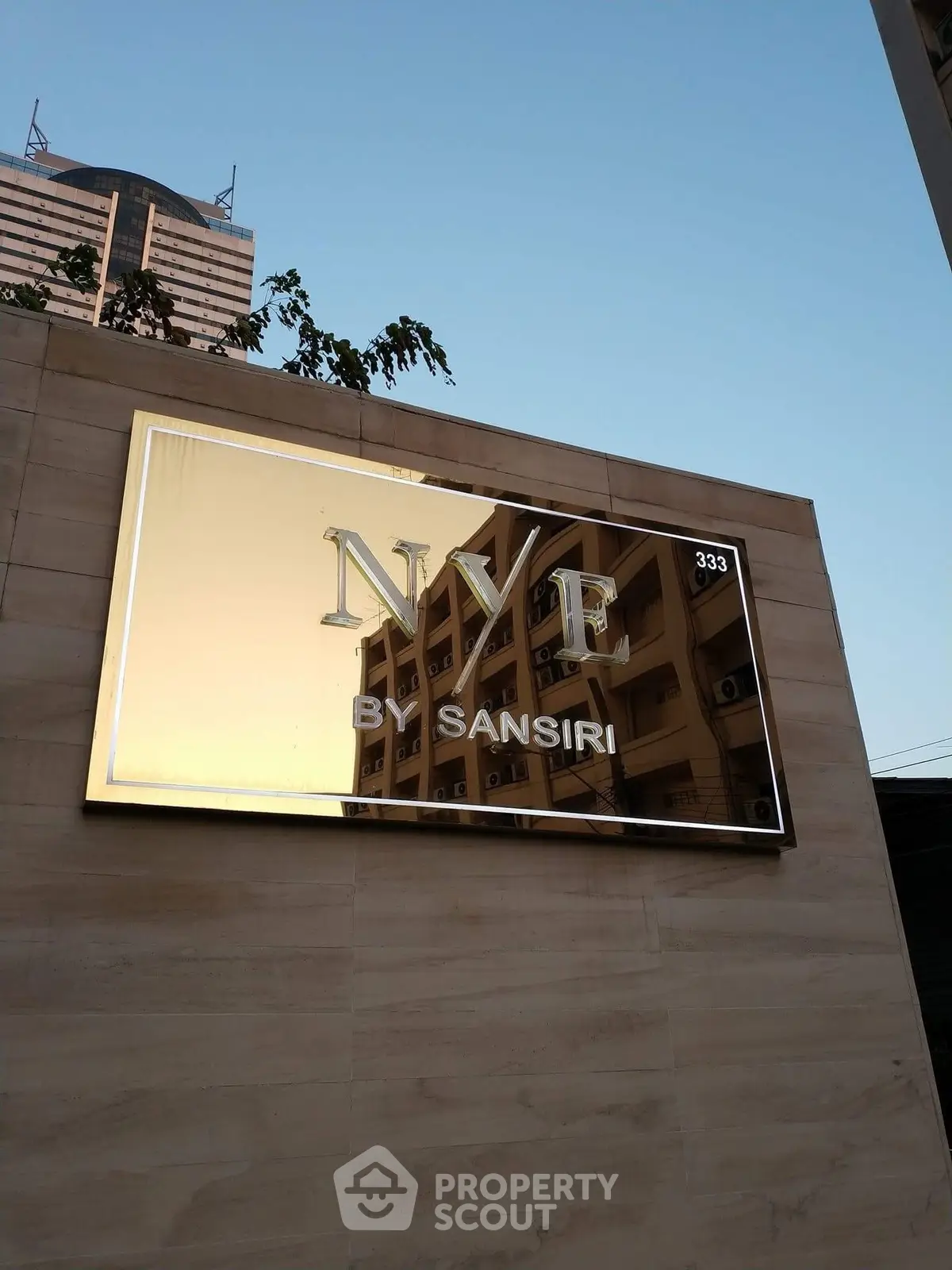 Modern building exterior with reflective sign displaying NYE by Sansiri.