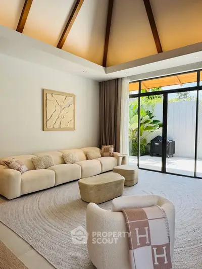 Luxurious living room with high ceilings and elegant decor, featuring a cozy seating area and large windows opening to a garden.