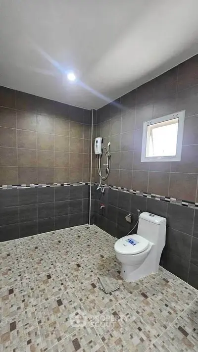 Modern bathroom with tiled walls and floor, featuring a toilet and shower area.