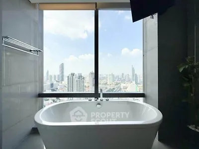 Luxurious bathroom with stunning city view from large window and modern bathtub.