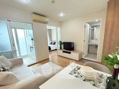 Modern open-plan living room with cozy seating and dining area, featuring a view into a stylish bedroom.