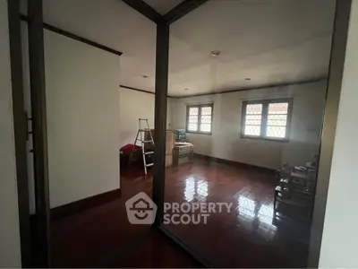 Spacious room with wooden floors and large windows, ideal for customization.