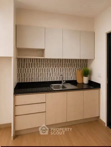 Modern kitchen with sleek cabinetry and stylish backsplash in a contemporary apartment.