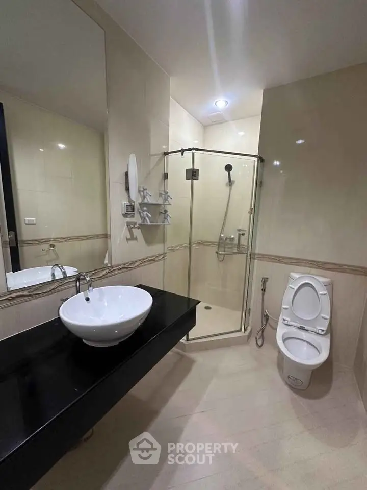 Modern bathroom with glass shower and sleek black countertop