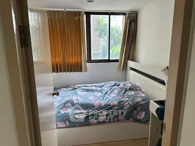 Cozy bedroom with floral bedding and large window offering natural light.