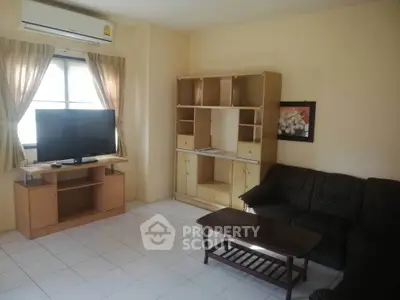 Cozy living room with natural light, featuring a TV, sofa, and wooden furniture for a comfortable home setting.